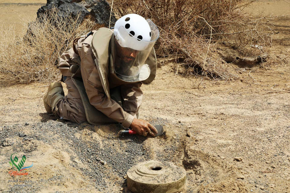 In this undated photograph released Aug. 19, 2018 by the state-run Emirates News Agency (WAM) on behalf of the Saudi-funded Masam anti-mine operation, an unidentified de-miner uncovers a mine near Marib, Yemen. Land mines scattered by Yemen’s Houthi rebels will remain a threat even if the latest negotiations succeed in halting the civil war. While the Houthis’ firing of ballistic missiles deep into Saudi Arabia has drawn the most attention, their widespread use of mines within Yemen represents a risk for generations to come in the Arab world’s poorest country. Yemen is also littered with unexploded cluster munitions and bombs dropped by the Saudi-led coalition, including some made in the United States. (WAM via AP)