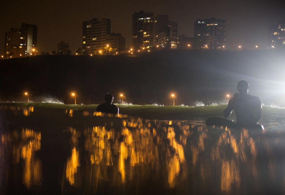 <p>Surfers wait for the right wave to catch in La Pampilla beach, Lima, in the middle of the night. The beach does not attract sharks; the greatest danger faced by night surfers is that they can crash into each other, blinded by the powerful floodlights. (AP Photo/Rodrigo Abd) </p>