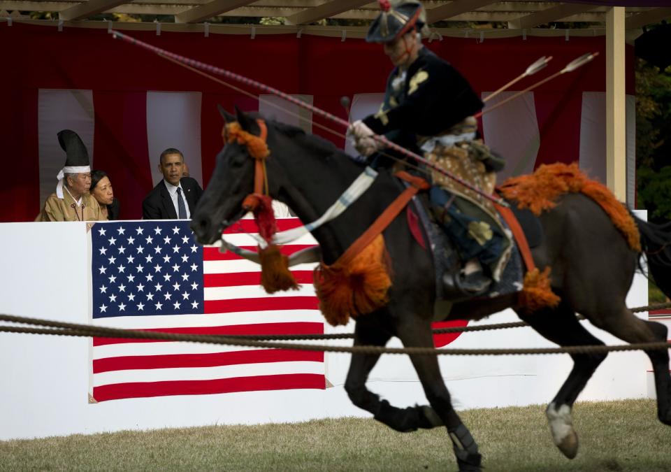 President Barack Obama watches a Yabusame or horseback archery demonstration as he tours Meiji Shrine in Tokyo, Thursday, April 24, 2014. Showing solidarity with Japan, Obama affirmed Thursday that the U.S. would be obligated to defend Tokyo in a confrontation with Beijing over a set of disputed islands, but urged all sides to resolve the long-running dispute peacefully. (AP Photo/Carolyn Kaster)