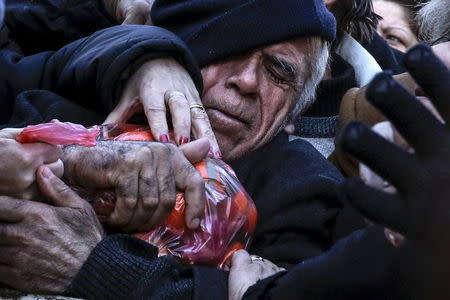 A man grasps a bag of tangerines as people receive free produce, handed out by farmers, during a protest over the government's proposal to overhaul the country's ailing pension system in Athens, Greece, January 27, 2016. REUTERS/Alkis Konstantinidis