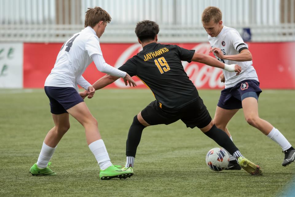 St. Joseph’s Ricky Aparicio tries to move the ball between American Heritage’s Carson Vonk, left, and Luke Stratton in a 2A boys soccer state semifinal at Zions Bank Stadium in Herriman on Wednesday, May 10, 2023. | Spenser Heaps, Deseret News