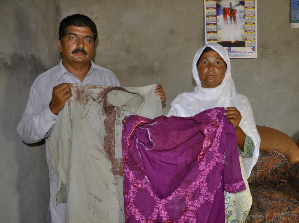 Pastor Haroon Sadiq Cheeda and his wife Mariam Haroon, who were beaten along with their son by Muslim neighbors and told to leave their village, show their blood-stains clothes, in a village in Rahim Yar Khan district, Pakistan, Monday, July 6, 2020. Analysts and activists say minorities in Pakistan are increasingly vulnerable to Islamic extremists as Prime Minister Imran Khan vacillates between trying to forge a pluralistic nation and his conservative Islamic beliefs. (AP Photo/Waleed Saddique)