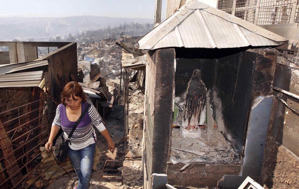 A resident walks past a religious image of the Virgin Mary after a forest fire burned several neighbourhoods in the hills in Valparaiso city