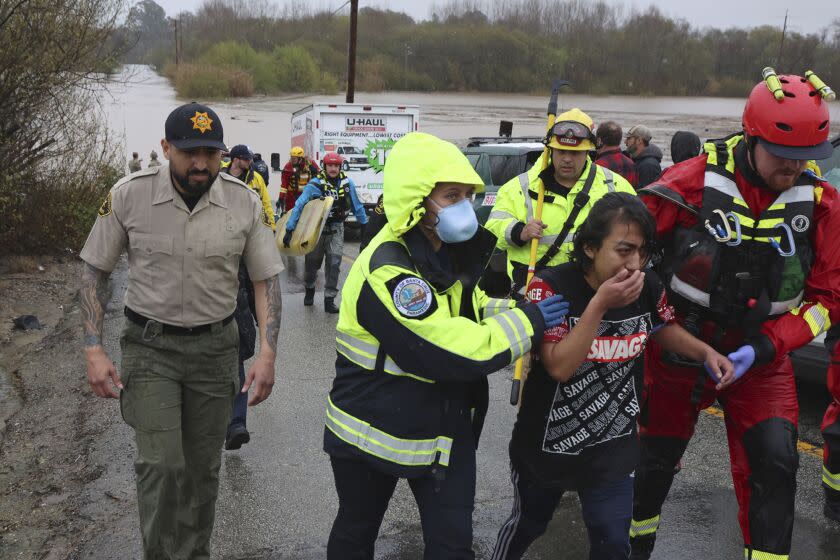 Lizbeth Hernandez is rescued from Casserly Creek after flood waters carried her truck off of Paulsen Road in Watsonville, Calif., Friday, March 10, 2023. Hernandez, who does not swim, stood on the roof of her submerged truck for over an hour until State Park swift water technicians Jeremy Paiss and Bryan Kine could reach her and paddle her to safety. (Shmuel Thaler/The Santa Cruz Sentinel via AP)