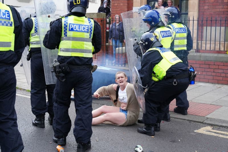 A police officer helps a fallen woman during an anti-immigration demonstration in Middlesbrough. After the knife attack on children in Southport on 29 July 2024, numerous nationalist and anti-Islamic protests inflame the mood in the UK. Owen Humphreys/PA Wire/dpa