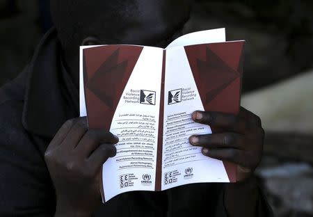 A Sudanese immigrant reads a pamphlet distributed by the UNHCR on racism in the western Greek town of Patras May 4, 2015. REUTERS/Yannis Behrakis