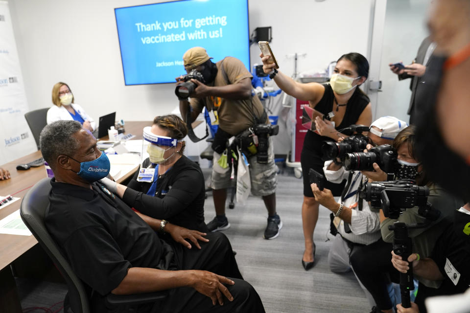 Nat Moore, 69, former Miami Dolphins football player, left, receives the Pfizer-BioNTech COVID-19 vaccine from registered nurse Susana Flores Villamil at Jackson Memorial Hospital, Wednesday, Dec. 30, 2020, in Miami. Jackson Health System is starting to vaccinate people over the age of 65 this week. (AP Photo/Lynne Sladky)