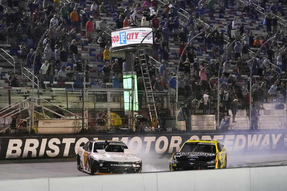 AJ Allmendinger, left, slides across the finish line ahead of Austin Cindric to win a NASCAR Xfinity Series auto race at Bristol Motor Speedway Friday, Sept. 17, 2021, in Bristol, Tenn. (AP Photo/Mark Humphrey)