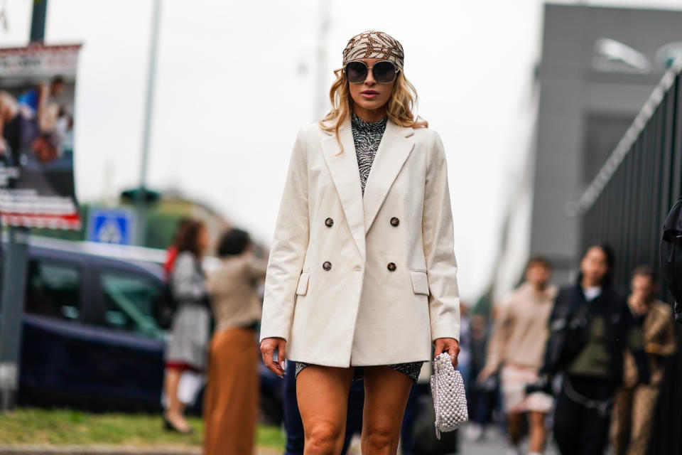 MILAN, ITALY - SEPTEMBER 22:  A guest wears sunglasses, a white and brown print hair scarf, a white corduroy double-breasted jacket, a white and black hi-neck speckled mini dress, a nacreous woven beadwork bag, outside the Gucci show during Milan Fashion Week Spring/Summer 2020 on September 22, 2019 in Milan, Italy. (Photo by Edward Berthelot/Getty Images)