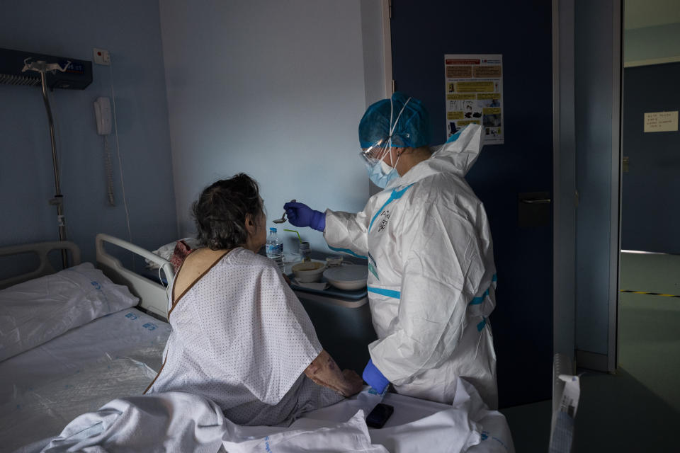 Nurse assistant Ainara Ruiz feeds a coronavirus patient in the Severo Ochoa Hospital in Leganes on the outskirts of Madrid, Spain, Wednesday, Feb. 17, 2021. (AP Photo/Bernat Armangue)