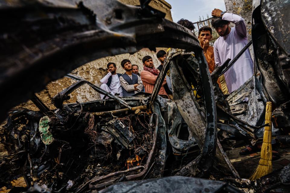 Relatives and neighbors of the Ahmadi family gathered around the incinerated husk of a vehicle that the family says was hit by a U.S. drone strike, in Kabul, Afghanistan, Monday, Aug. 30, 2021. (Marcus Yam/Los Angeles Times/TNS)