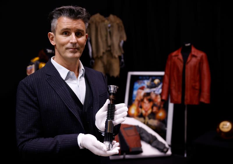 Stephen Lane, CEO of Prop Store, poses for a photograph with Obi-Wan Kenobi's Hero Lightsaber from Star Wars: Revenge of the Sith, at a preview of a movie and TV memorabilia auction in Rickmansworth