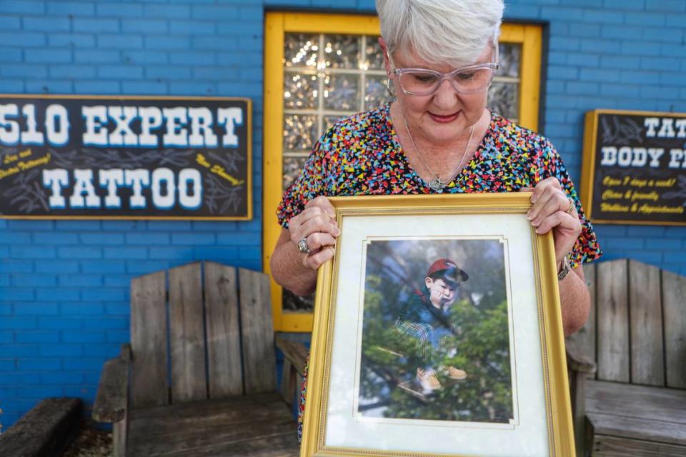 Kelly Kennedy, outside the tattoo shop where her son worked, holds a framed childhood picture of her son, Logan McAdams. He died on April 30, 2022, in Charlotte, from fentanyl overdose.