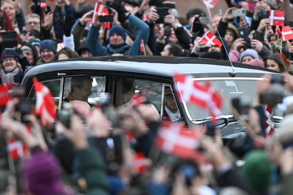 People rise mobile devices and wave flags of Denmark as Crown Prince Frederik of Denmark C-L) and Crown Princess Mary of Denmark (C-R) ride from the Amalienborg Castle to the Christiansborg Castle, during the proclamation of abdication of Denmark's Queen Margrethe II, in Copenhagen (AFP via Getty Images)