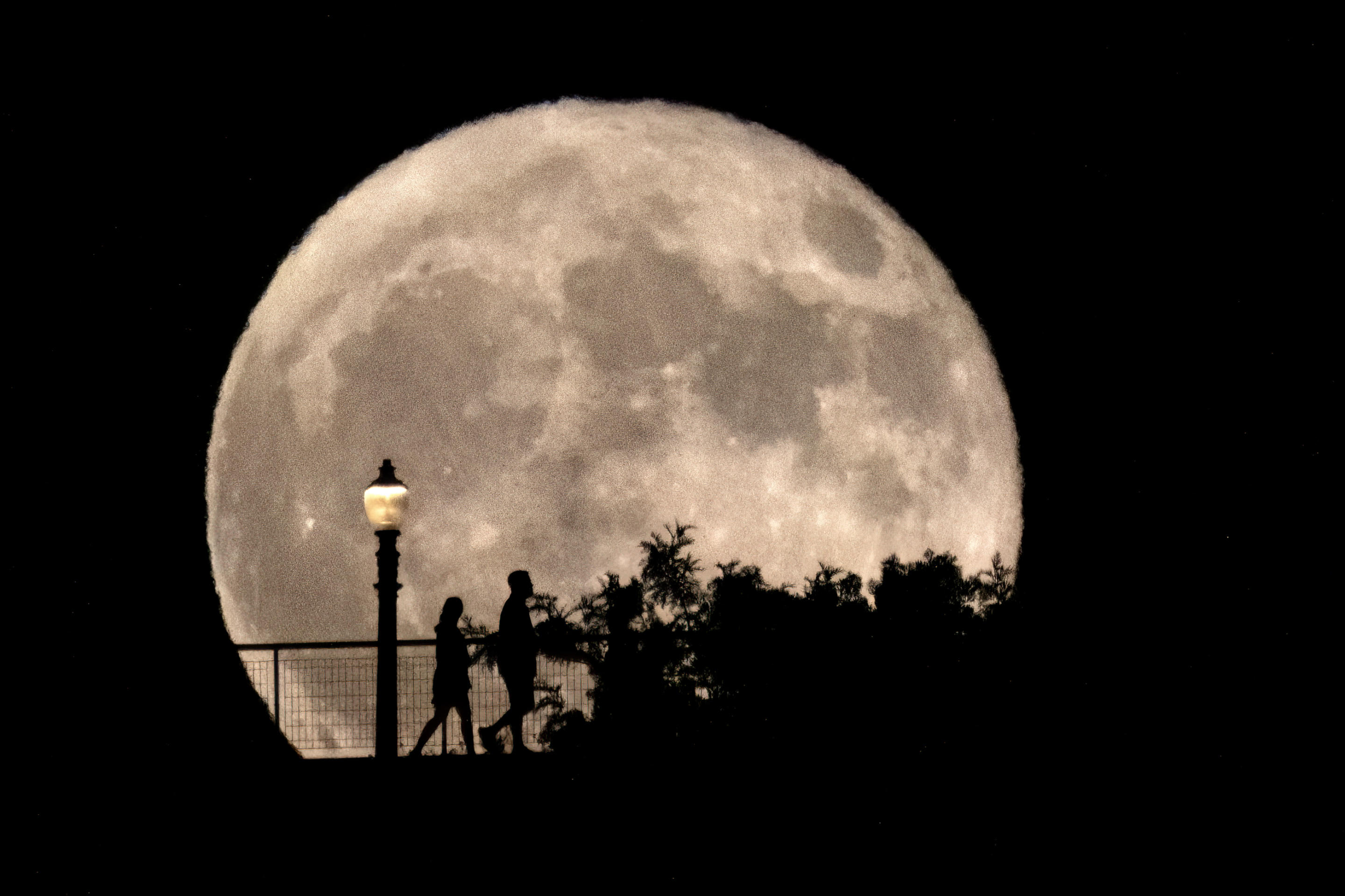 People walk past a rising supermoon at the Griffith Observatory in Los Angeles on Monday, August 19, 2024. (Richard Vogel/AP)