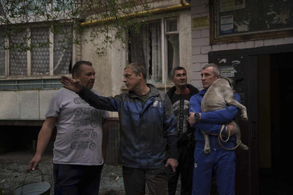 Residents talk outside a burning apartment building following a Russian bombardment in Kharkiv, Ukraine, Monday, April 25, 2022. (AP Photo/Felipe Dana)