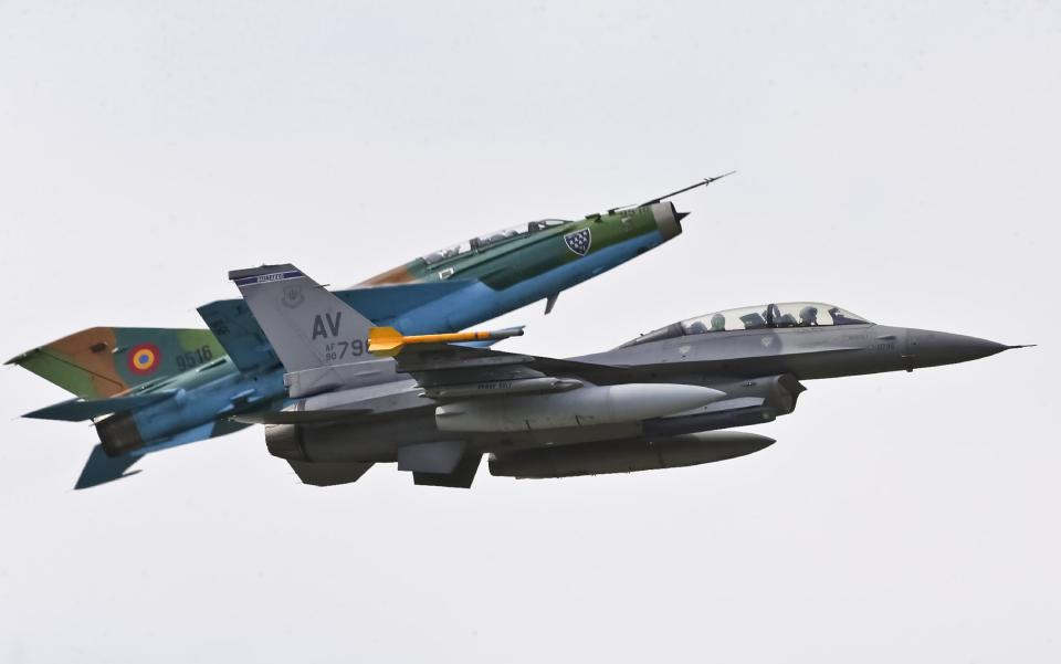 A Russian made MIG 21 fighter jet maneuvers next to a US Air Force F-16 piloted by Maj. Dustin Yogi Brown, right, and transporting Romanian Premier Victor Ponta during a military exercise in Campia Turzii, Romania, Thursday, April 17, 2014. Dressed in a flight suit, Ponta visited the Campia Turzii military air base in northwest Romania where about 450 U.S. and Romanian troops and technical staff had been taking part in the weeklong exercises ending Thursday. (AP Photo/Mircea Rosca)