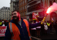 A rail worker lights a flare during a mass strike in Lille, northern France, Thursday, Dec. 5, 2019. Workers across the public sector fear President Emmanuel Macron's reform will force them to work longer and shrink their pensions. (AP Photo/Michel Spingler)