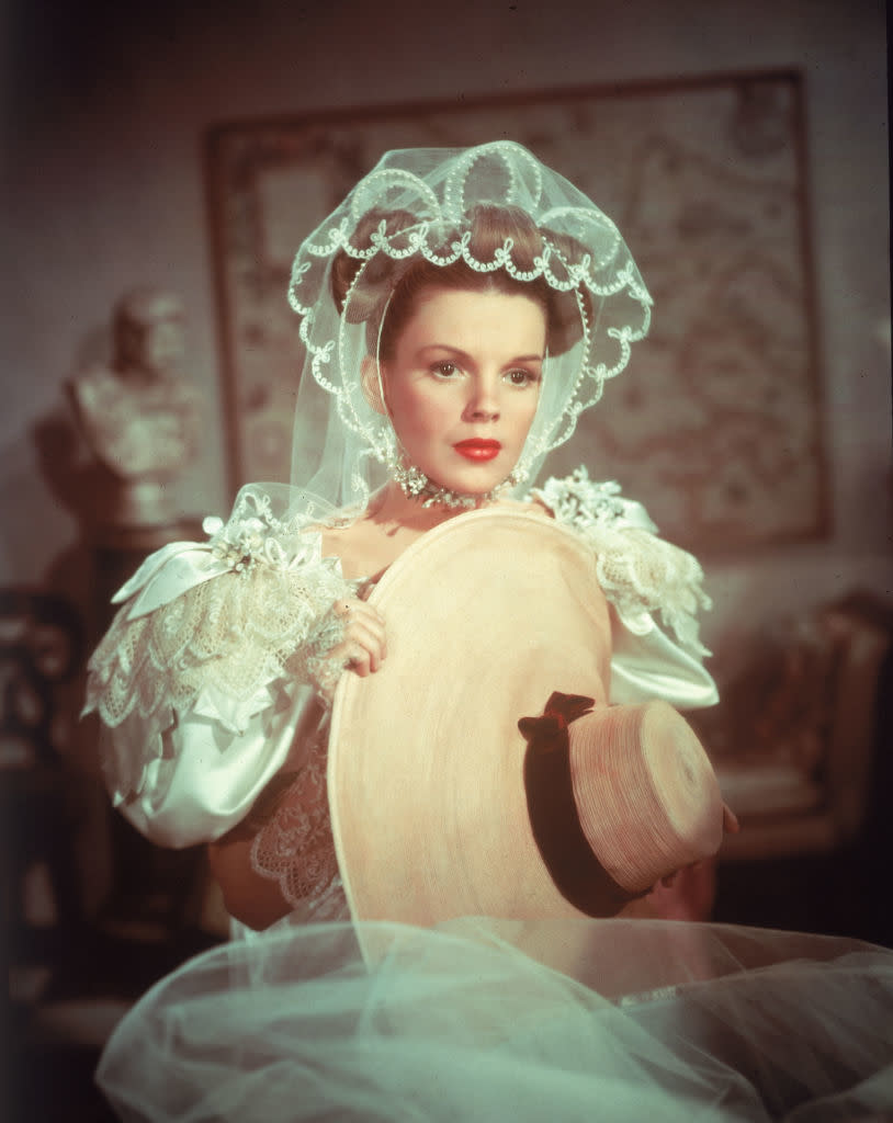 Judy in vintage bridal gown and lace veil holding a hat