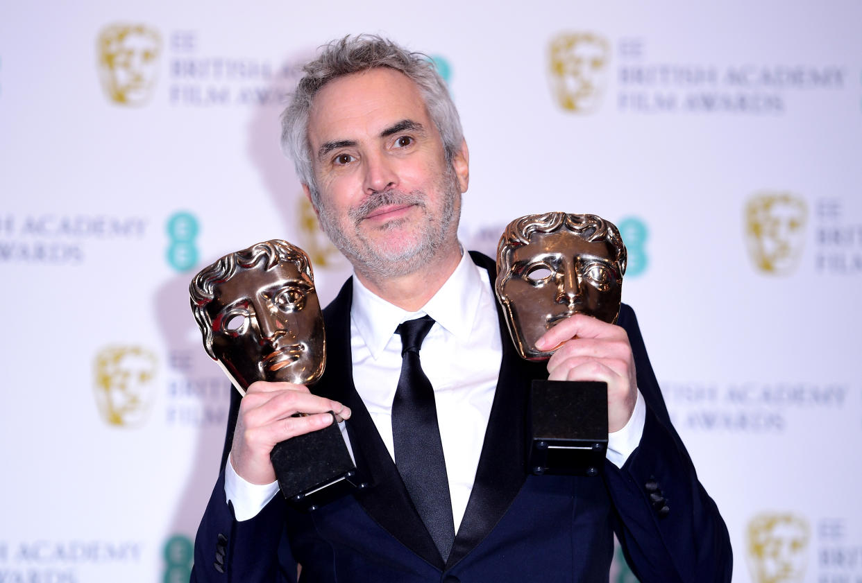 Alfonso Cuaron holds aloft two of his BAFTAs for <i>Roma</i> (PA)