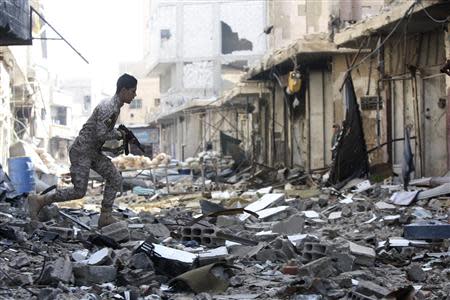 A Shi'ite fighter, fighting along forces loyal to Syria's President Bashar al-Assad, carries his weapon as he runs along a deserted street in Hujaira town, south of Damascus November 20, 2013. REUTERS/Alaa Al-Marjani