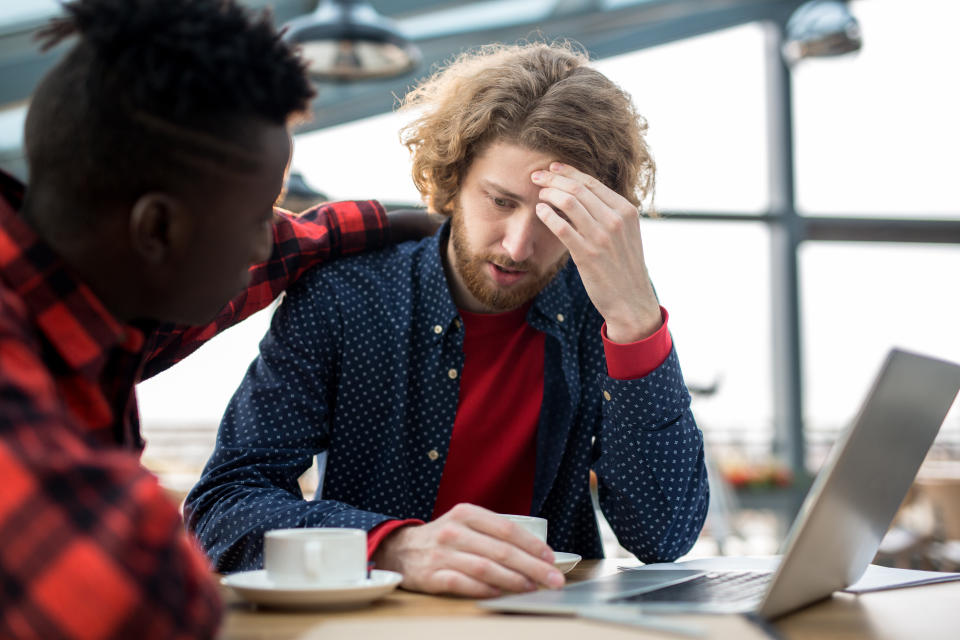 Worried businessman touching forehead while sharing his problems with colleague by cup of coffee