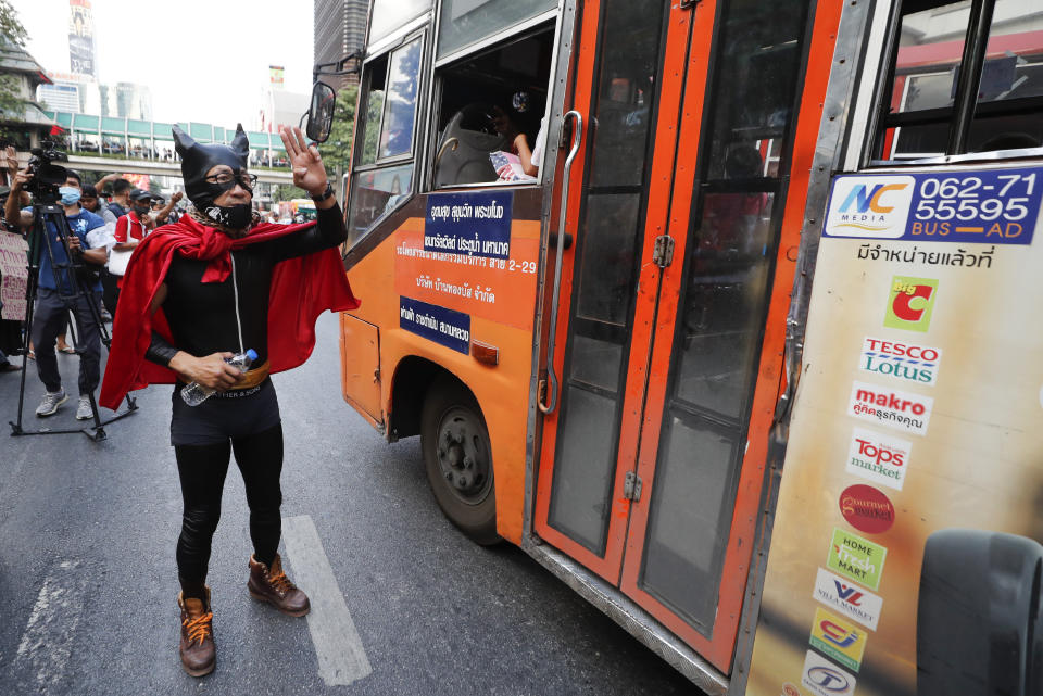 A Pro-democracy protester dressed in costume flash the three-finger protest salute at a major intersection in Bangkok, Thailand, Wednesday, Nov. 18, 2020. Police in Thailand's capital braced for possible trouble Wednesday, a day after a protest outside Parliament by pro-democracy demonstrators was marred by violence that left dozens of people injured. (AP Photo/Sakchai Lalit)