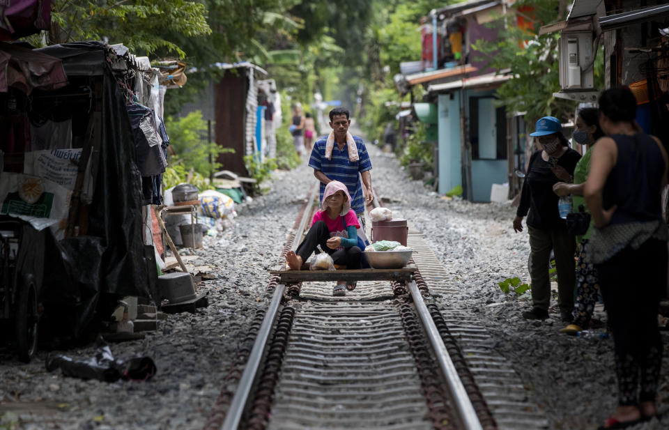 A vendor pushes an improvised cart with a woman and merchandise along a rarely used rail track in Bangkok, Thailand, Thursday, June 25, 2020. Daily life in the capital slowly returns to normal as the Thai government eases many restrictions imposed weeks ago to combat the spread of COVID-19. Though emergency regulations require the use of face masks in public, some residents have become apathetic as Thailand has record zero local transmission for over three weeks. (AP Photo/ Gemunu Amarasinghe)