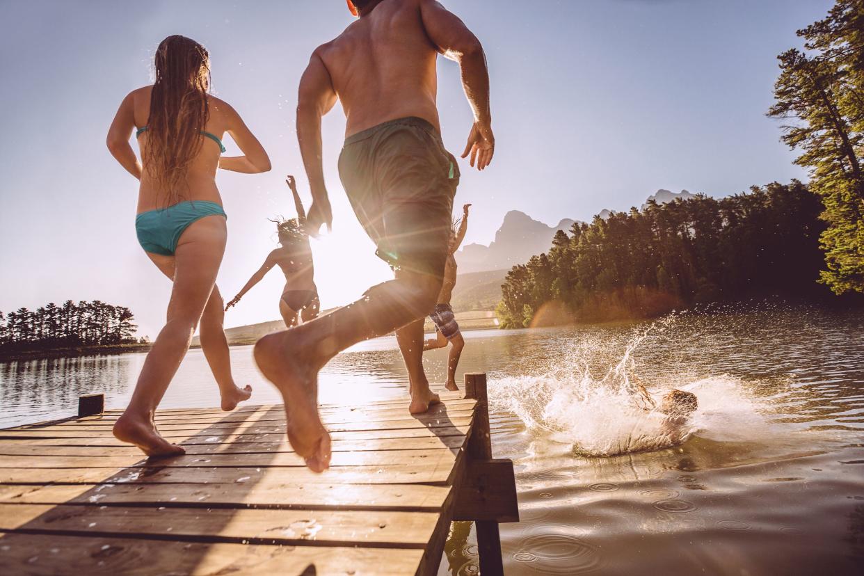 people jumping into lake from a jetty