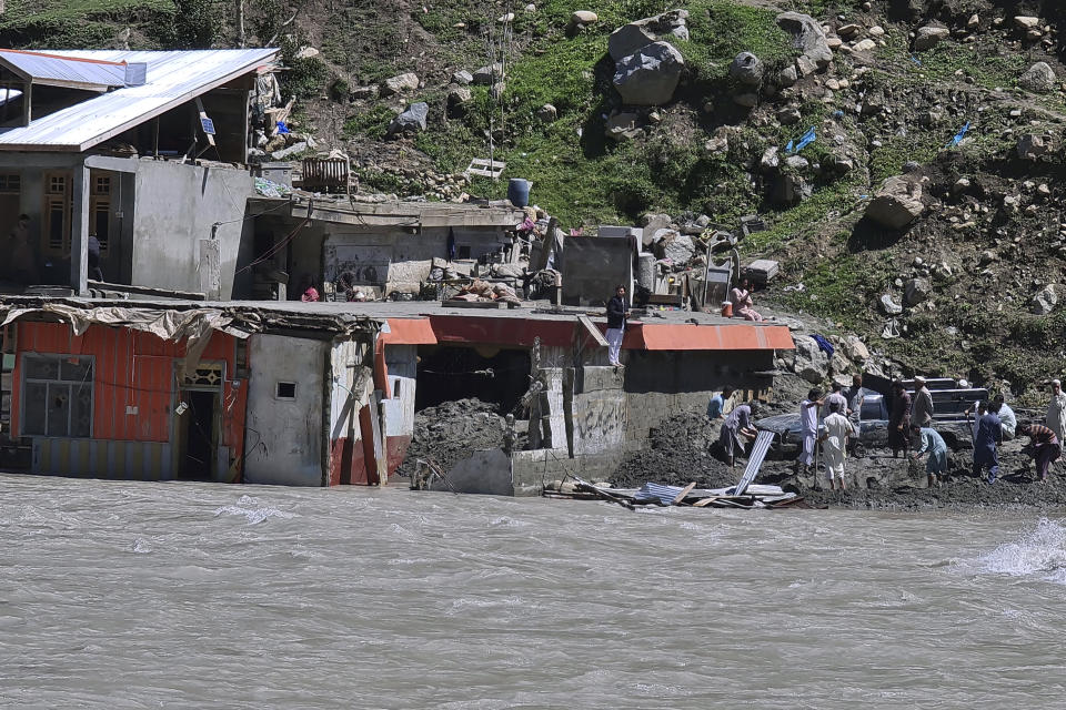 People salvage usable items from a damaged hotel building caused by floodwaters, in the village of Kalam in the Swat Valley, Pakistan, Tuesday, Aug. 30, 2022. Disaster officials say nearly a half million people in Pakistan are crowded into camps after losing their homes in widespread flooding caused by unprecedented monsoon rains in recent weeks. (AP Photo/Sherin Zada)