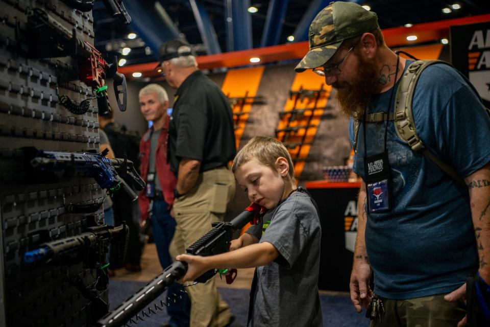 Chris Shelton, 36, oversees his son Luke Shelton, 7, trying out an AR-15 at the 2022 NRA convention