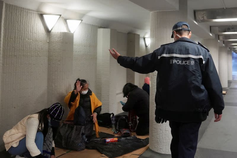 FILE PHOTO: A police officer instructs domestic workers gathering on their rest day to leave, during a coronavirus disease (COVID-19) outbreak in Hong Kong, China