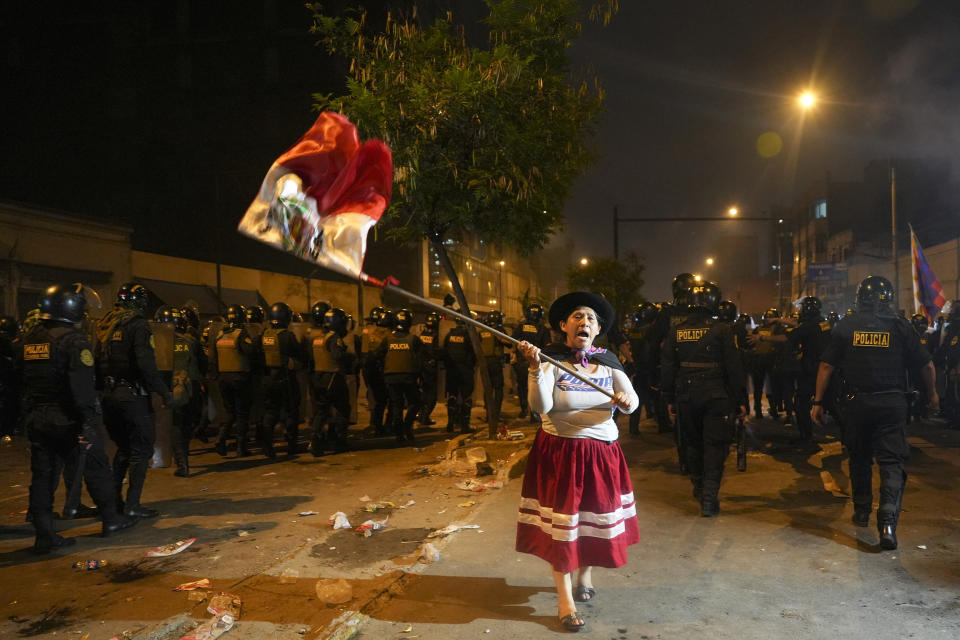 A woman waves a Peruvian flag during an anti-government protest in Lima, Peru, Friday, Jan. 20, 2023. Protesters are seeking the resignation of President Dina Boluarte, the release from prison of ousted President Pedro Castillo and immediate elections. (AP Photo/Guadalupe Pardo)