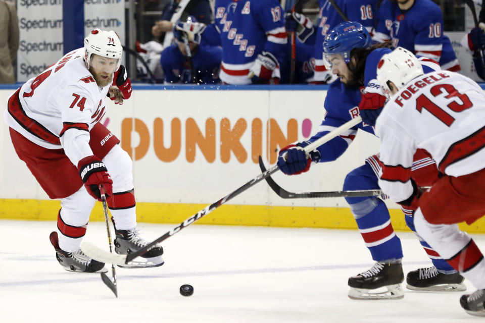 New York Rangers center Mika Zibanejad, second from right, blocks Carolina Hurricanes defenseman Jaccob Slavin (74) from getting to the puck as Hurricanes left wing Warren Foegele (13) defends Zibanejad during the first period of an NHL hockey game Friday, Dec. 27, 2019, in New York. (AP Photo/Kathy Willens)