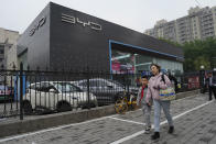 Residents past by a Seagull electric vehicle from Chinese automaker BYD parked at a showroom in Beijing, Wednesday, April 10, 2024. The tiny, low-priced electric vehicle called the Seagull has American automakers and politicians trembling. The car, launched last year by Chinese automaker BYD, sells for around $12,000 in China. But it drives well and is put together with craftsmanship that rivals U.S.-made electric vehicles that cost three times as much. Tariffs on imported Chinese vehicles probably will keep the Seagull away from America’s shores for now.(AP Photo/Ng Han Guan)