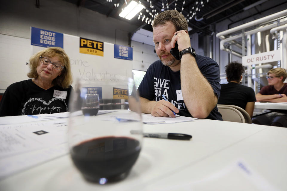 Democratic presidential candidate Pete Buttigieg supporter Zach Norton, right, talks on his cell phone during a "relational phone bank" at a local brewery, Thursday, Aug. 29, 2019, in West Des Moines, Iowa. The group worked their smartphones calling and texting friends to test their interest in the candidate. Buttigieg is well behind his better known rivals in Iowa who have spent months building a deep organizational structure in the state that marks the first test for the Democratic presidential nomination. But thanks to his campaign taking in nearly $25 million in contributions in the last quarter, money that he is using to help create an army of peer-to-peer foot soldiers, Buttigieg is rapidly trying to catch up. (AP Photo/Charlie Neibergall)