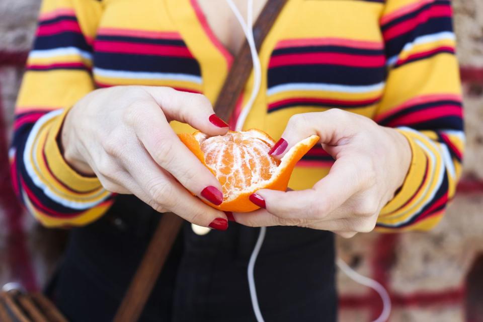 woman's hands peeling tangerine, close up