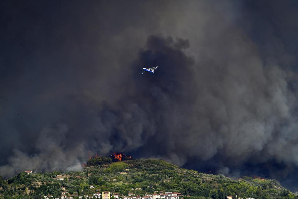 A Russian aircraft operates during a wildfire near ancient Olympia, Wednesday, Aug. 4, 2021. Greece evacuated people in boats from an island beach Wednesday amid heavy smoke from a nearby wildfire and fire crews fought elsewhere to keep flames away from the birthplace of the ancient Olympic Games as the country sweltered under a record heat wave. (Giannis Spyrounis/ilialive.gr via AP)