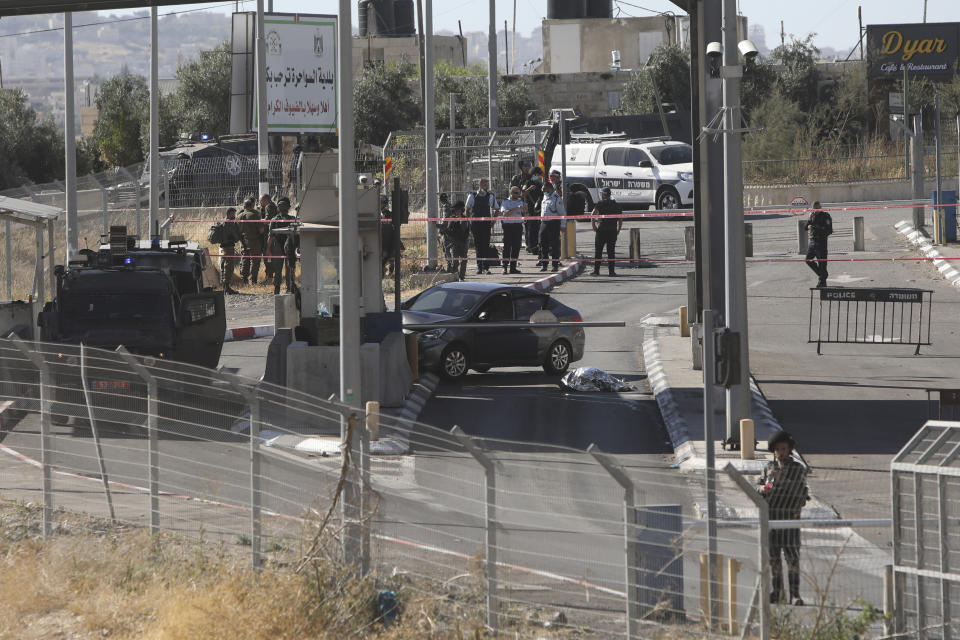 Israeli policemen stand around the body of a Palestinian at a checkpoint near Jerusalem, Tuesday, June 23, 2020. A Palestinian driver died Tuesday after he was shot by an Israeli policeman at a checkpoint in the West Bank in what police said was an attempted attack on Israeli military personnel. (AP Photo/Mahmoud Illean)