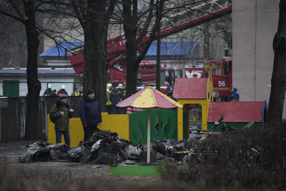People look at remains of helicopter in a kindergarten at the scene where a helicopter crashed on civil infrastructure in Brovary, in the outskirts of Kyiv, Ukraine, Wednesday, Jan. 18, 2023. The chief of Ukraine's National Police says a helicopter crash in a Kyiv suburb has killed 16 people, including Ukraine's interior minister and two children. He said nine of those killed were aboard the emergency services helicopter. (AP Photo/Daniel Cole)