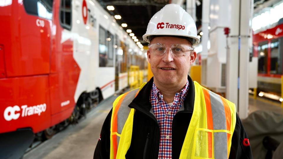 Michael Morgan, Ottawa's rail construction director, stands between a Stadler FLIRT train and an Alstom LINT train at the new Albion Maintenance and Storage Facility. 