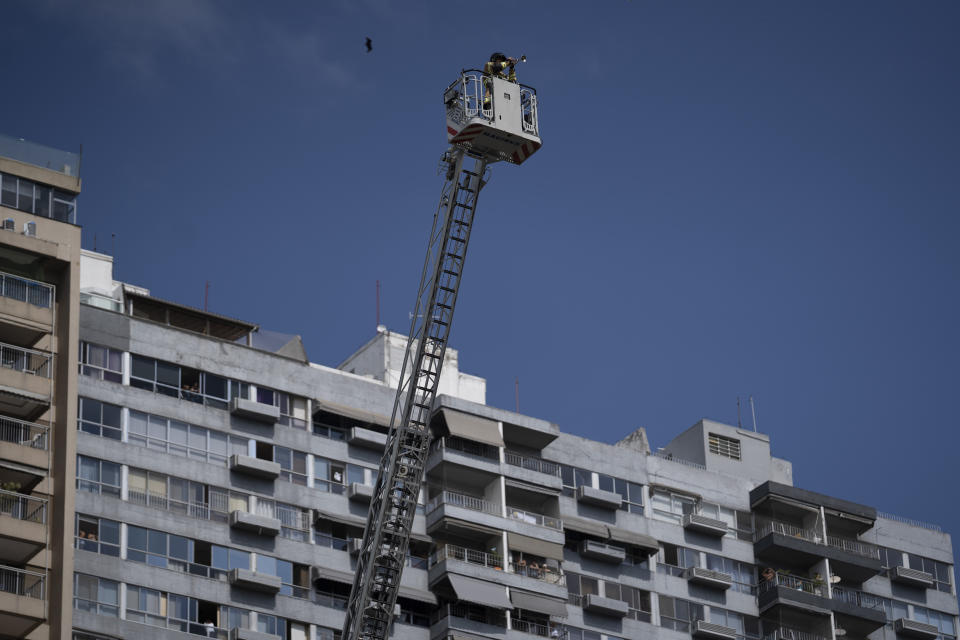 Firefighter Elielson Silva plays his trumpet on the top of a ladder for residents cooped up at home, during a lockdown to help contain the spread of the new coronavirus in Rio de Janeiro, Brazil, Sunday, April 5, 2020. As he played in several Rio neighborhoods on Sunday, his final numbers were Brazil’s national anthem, then “Hallelujah.” (AP Photo/Leo Correa)