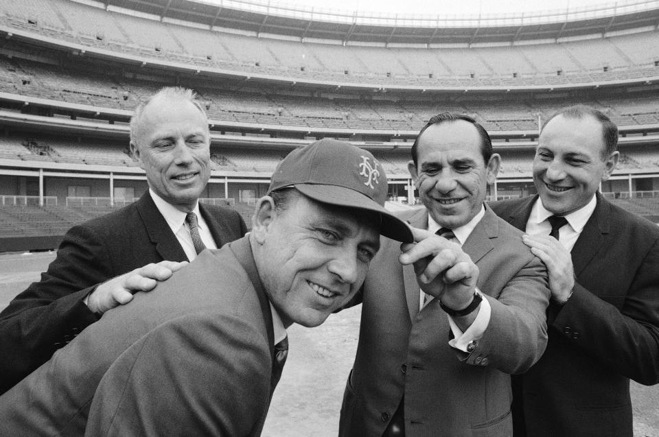 FILE - Gil Hodges, second from left, the new New York Mets manager, wears a team cap with an added touch by first base coach Yogi Berra, second from right, as Bing Devine, left, president of the team, and Joe Pignatano, right, newly signed as the team's bullpen coach, watch during a visit to Shea Stadium, Oct. 17, 1967, in New York. Pignatano, who made his major league debut with the Brooklyn Dodgers in 1957 and later was a coach for the Mets, died Monday, May 23, 2022, in Naples, Fla. (AP Photo/Harry Harris, File)