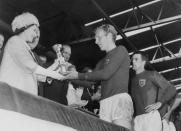 Queen Elizabeth presents the Jules Rimet Cup to Bobby Moore, captain of the England team, as her husband Prince Philip and hat trick hero Geoff Hurst look on after England beat West Germany 4-2 World Cup final 1966 at Wembley stadium. (STAFF/AFP via Getty Images)