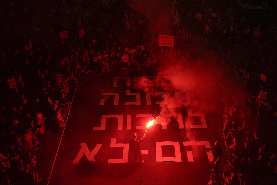 A demonstrator holds up a flare during a protest calling for the release of the Israeli hostages held in the Gaza Strip by the Hamas militant group, in Tel Aviv, Monday, April 29, 2024. (AP Photo/Ohad Zwigenberg)