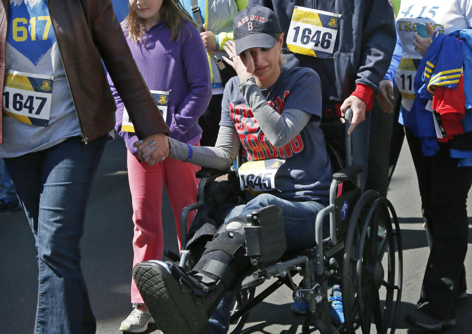 Boston Marathon bombings survivor Rebekah Gregory DiMartino wipes tears as she is led in her wheelchair after crossing the finish line of the Boston Marathon Tribute Run in Boston, Saturday, April 19, 2014. (AP Photo/Elise Amendola)