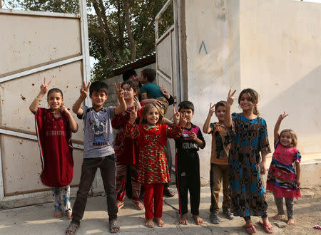 Children gesture as Kurdish Peshmerga fighters (not seen) arrive after recapturing the Fadiliya village from Islamic state militants, in Nawaran, north of Mosul, Iraq, October 27, 2016. REUTERS/Air Jalal