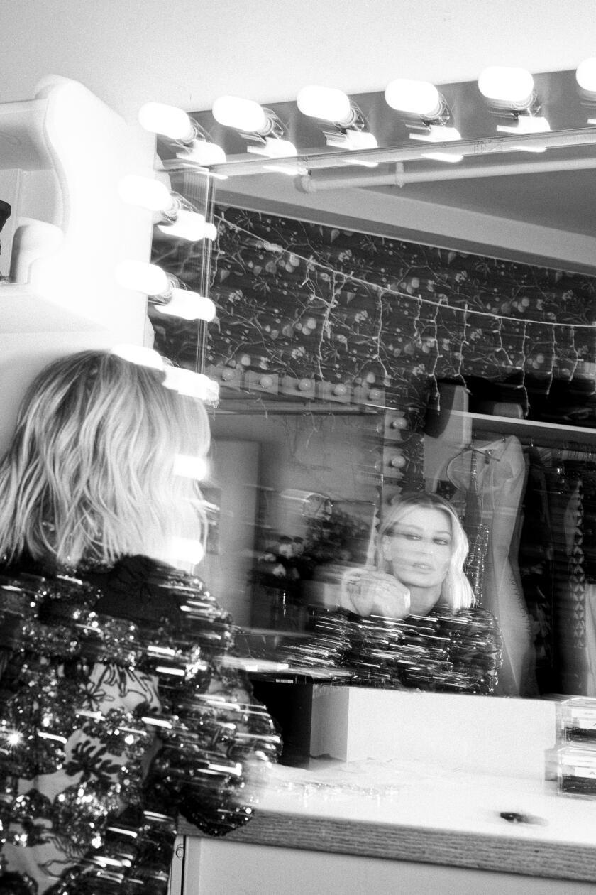 A blurry black-and-white photo of Ariana Madix looking at herself in dressing room mirror