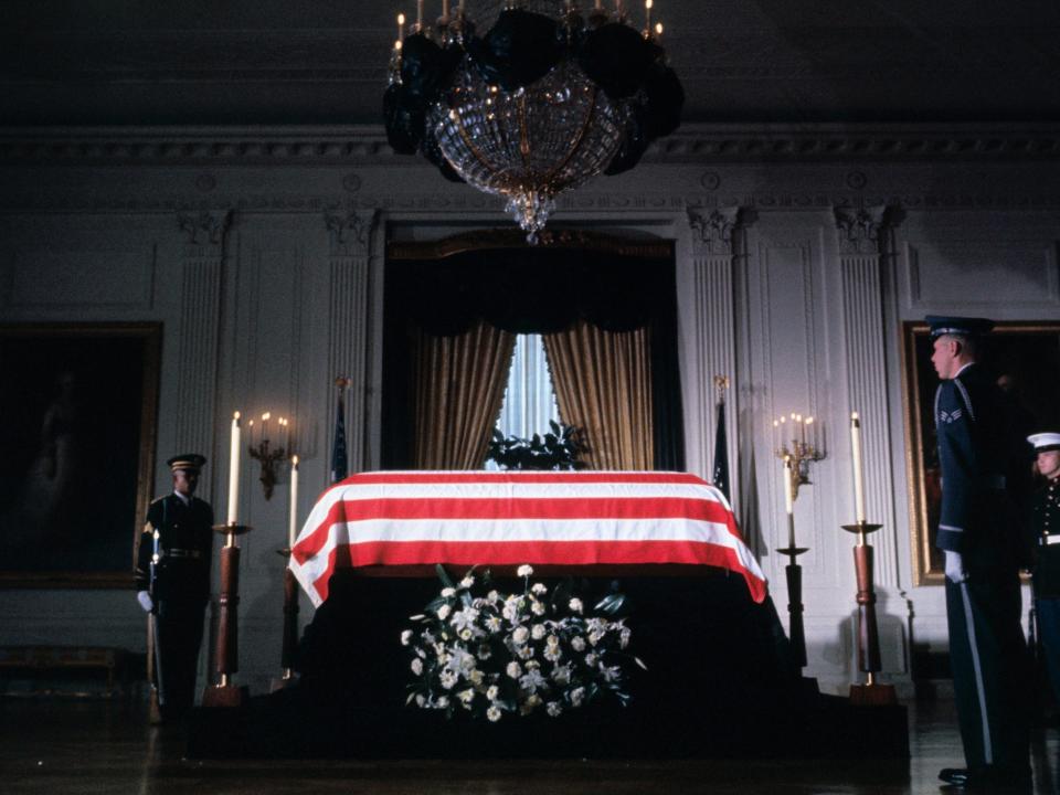 Black bunting hangs from chandelier in East Room of the White House, as the body of late President John F. Kennedy lies in state with military honor guard standing by.