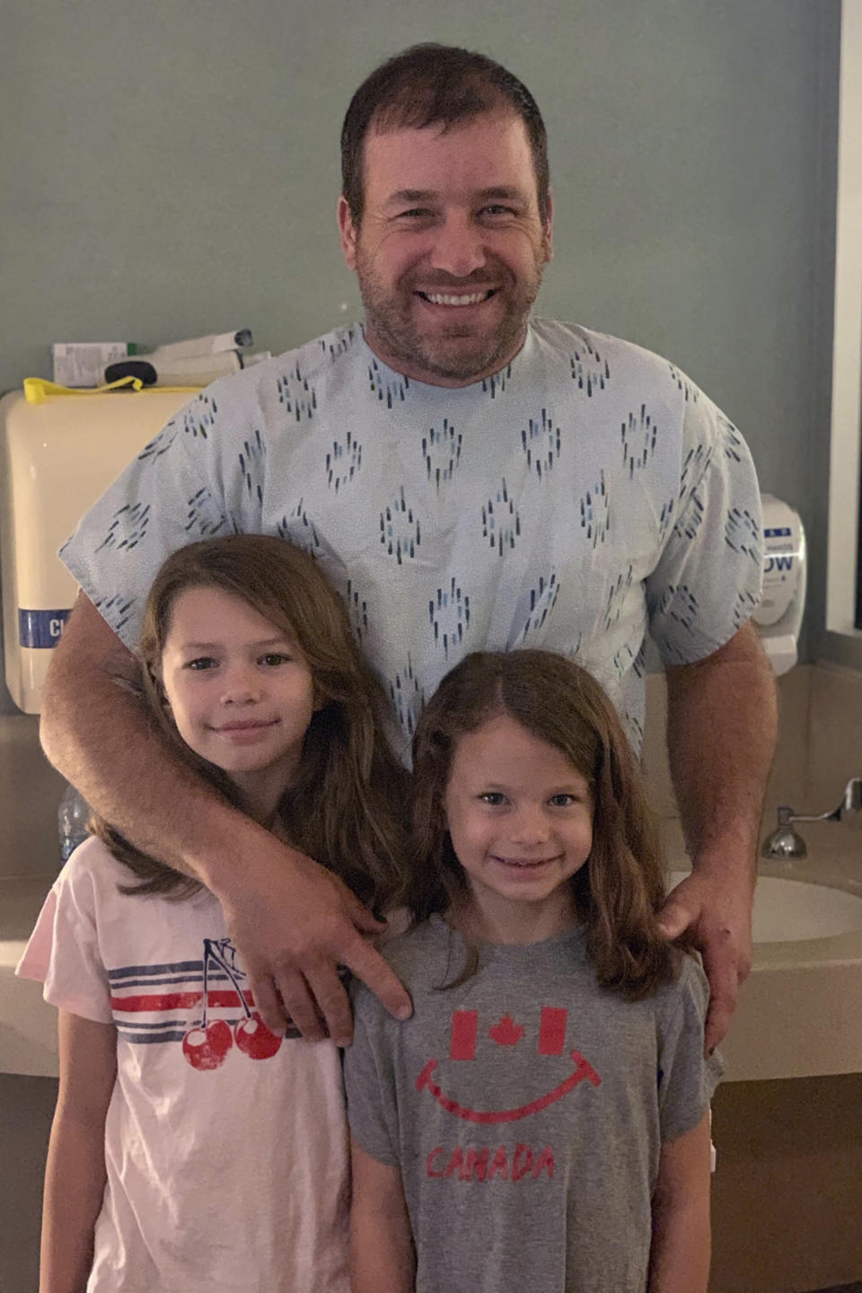 This undated photo provided by Roush Racing shows NASCAR driver Ryan Newman and his daughters, Brooklyn Sage, left, and Ashlyn Olivia, at Halifax Medical Center in Daytona Beach, Fla. Newman is fully alert, walking around the hospital and joking with staff two days after his frightening accident on the final lap of the Daytona 500 auto race. Roush Fenway Racing said Wednesday, Feb. 19, 2020, the 42-year-old “continues to show great improvement.” (Roush Racing via AP)